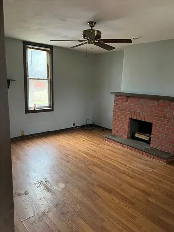 an empty room with wooden floor a fireplace and windows