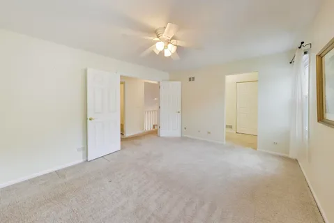 an empty room with closet and a chandelier fan