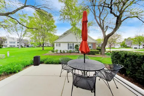 a view of a backyard with table and chairs potted plants and large trees