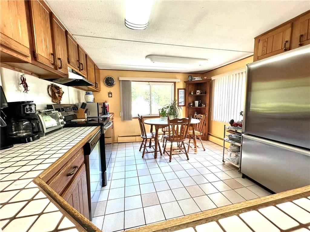 12 Mesmer Hill Road Callicoon, NY 12723 - Photo 5 of 18 Kitchen with tile counters, appliances with stainless steel finishes, a baseboard radiator, and light tile flooring