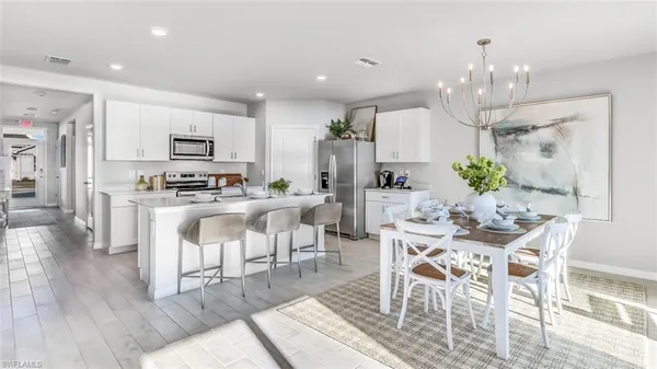 a view of kitchen with microwave stove refrigerator dining table and chairs