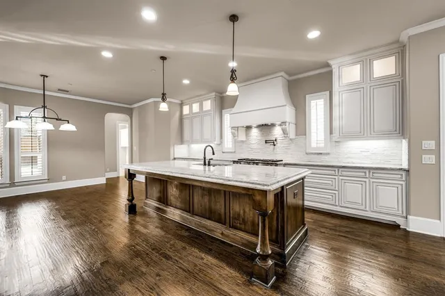 a large kitchen with granite countertop a large window and white cabinets