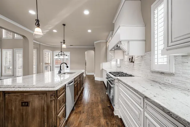 a kitchen with stainless steel appliances granite countertop a sink a stove and a wooden floors