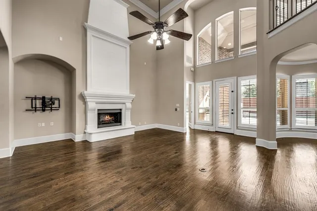 a view of an empty room with wooden floor and a fireplace