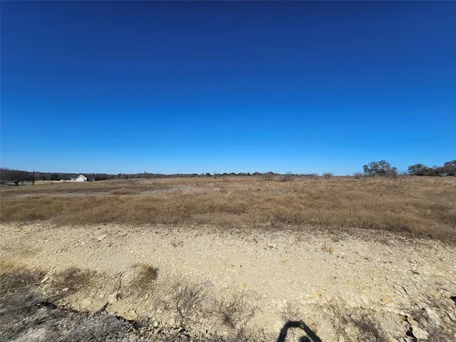 a view of a dry field with trees in the background