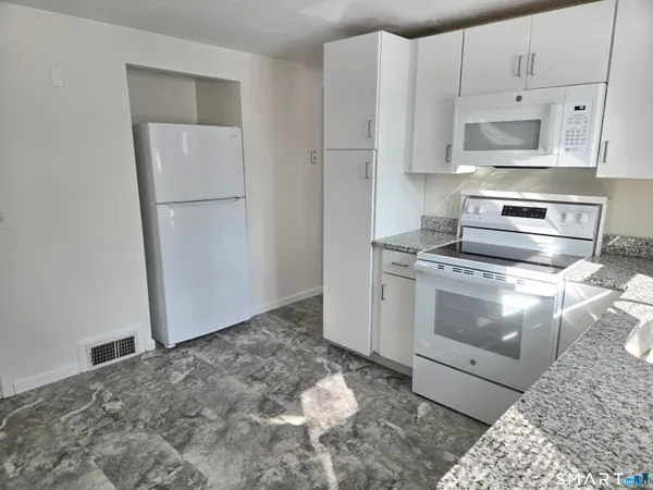 a kitchen with white cabinets and white appliances