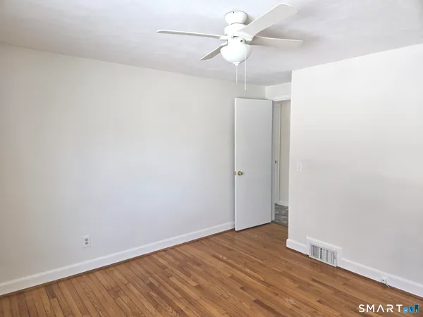an empty room with wooden floor fan and windows