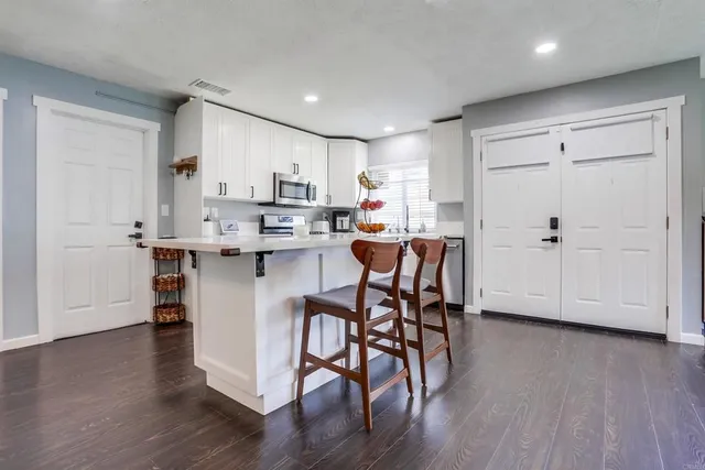 a kitchen with stainless steel appliances a dining table chairs and wooden floor