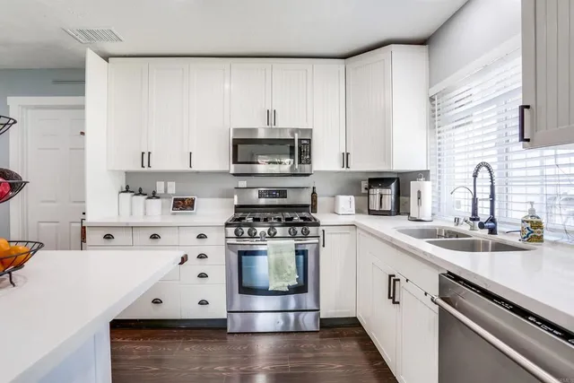 a kitchen with stainless steel appliances white cabinets sink and stove