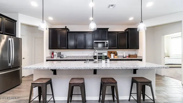 a large kitchen with granite countertop white cabinets and stainless steel appliances