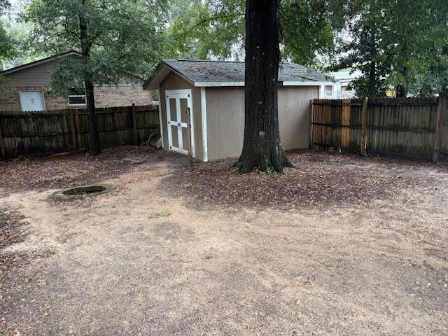 a view of a yard with large trees and wooden fence
