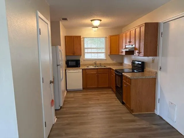 a kitchen with stainless steel appliances granite countertop a stove top oven a sink and dishwasher