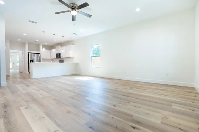 an empty room with wooden floor and a ceiling fan