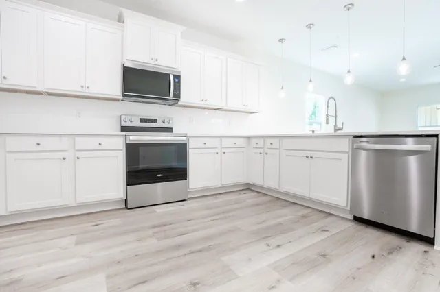 a kitchen with granite countertop white cabinets stainless steel appliances and sink