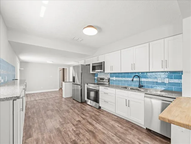 a kitchen with granite countertop a sink stove and refrigerator