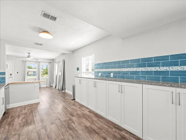 a view of a kitchen with a sink and dishwasher with wooden floor
