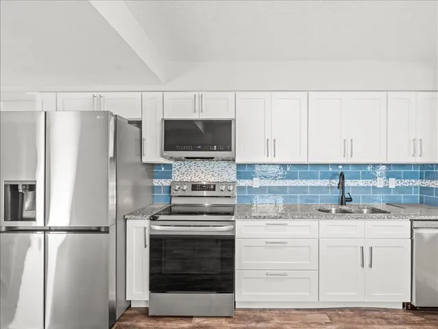 a kitchen with a refrigerator stove and white cabinets