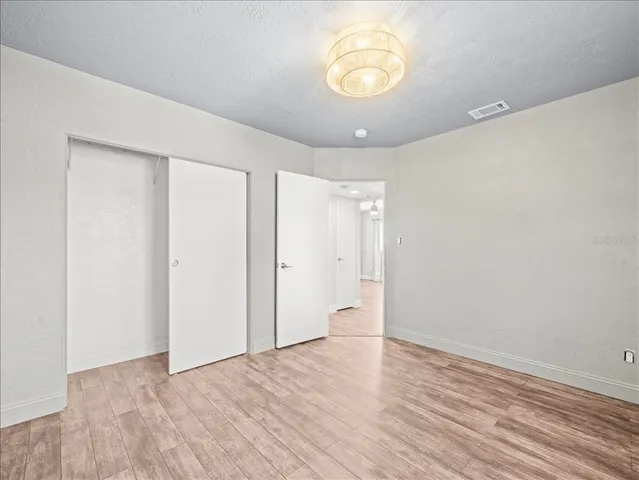 a view of an empty room with a window and wooden floor