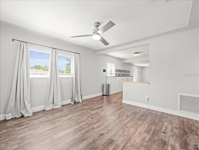 an empty room with wooden floor cabinet and windows