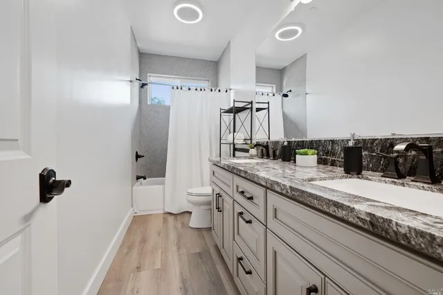a bathroom with a granite countertop sink a toilet a mirror and shower