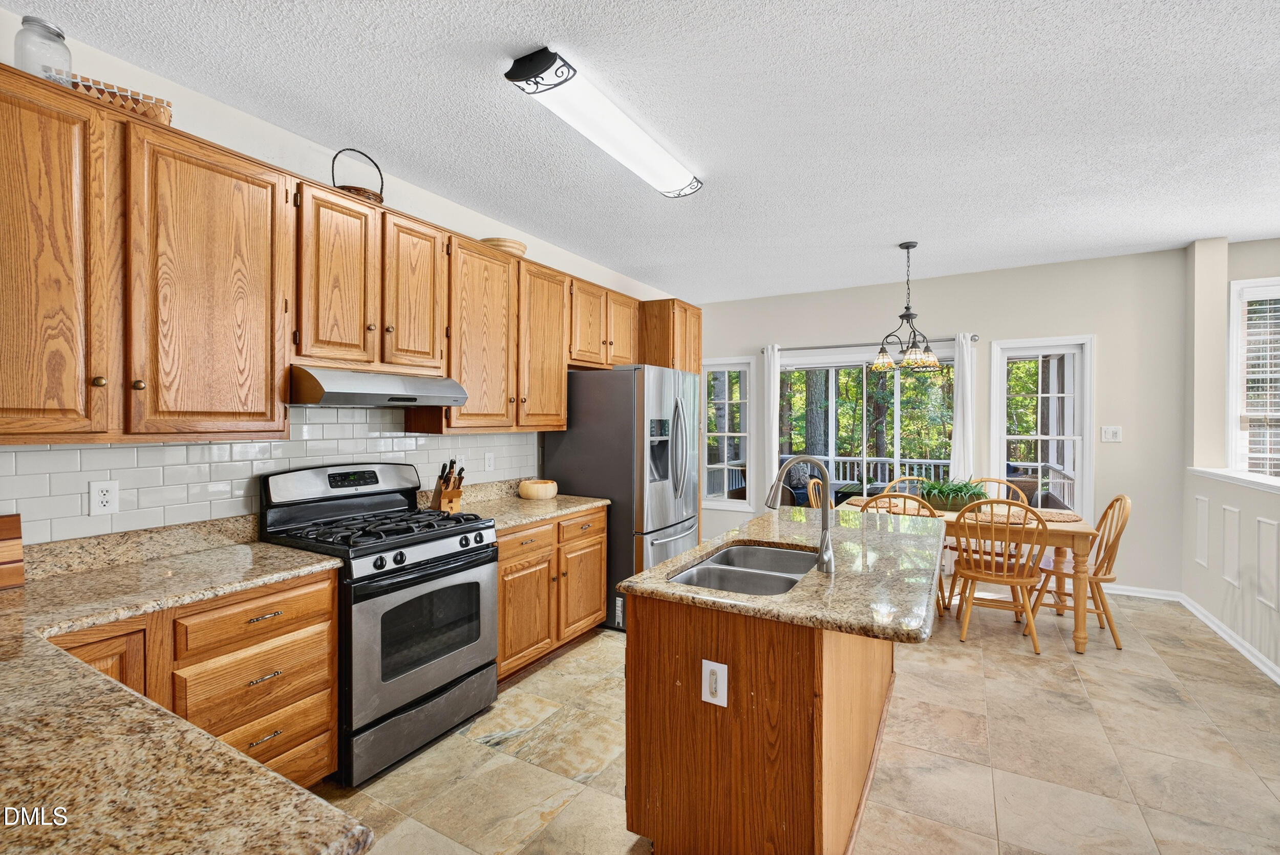105 Point Harbor Drive Cary, NC 27519 - Photo 5 of 39 a kitchen with stainless steel appliances granite countertop a stove top oven a sink dishwasher a dining table and chairs with wooden floor