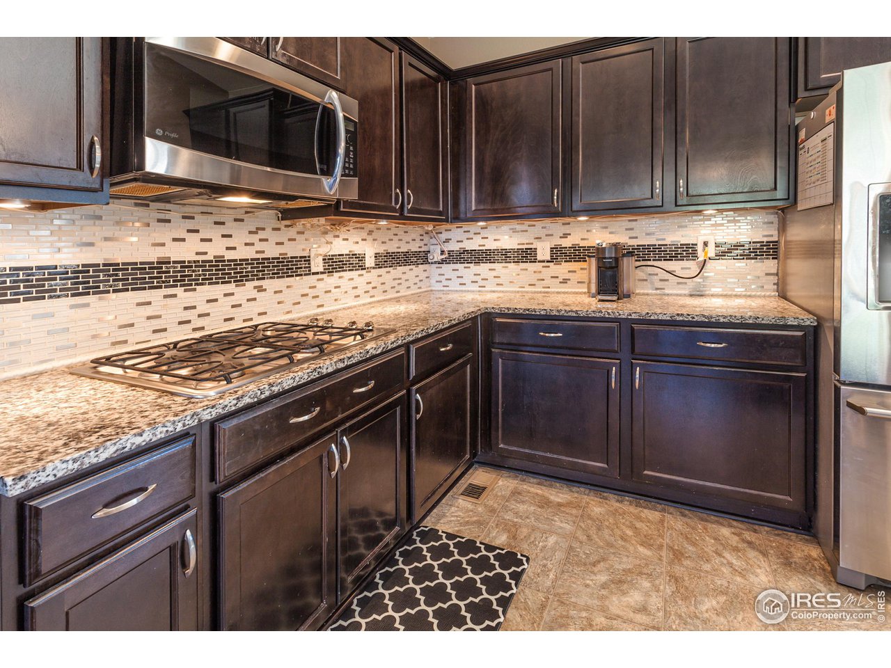 8594 Raspberry Drive Frederick, CO 80504 - Photo 8 of 40 a kitchen with stainless steel appliances granite countertop a sink stove and microwave