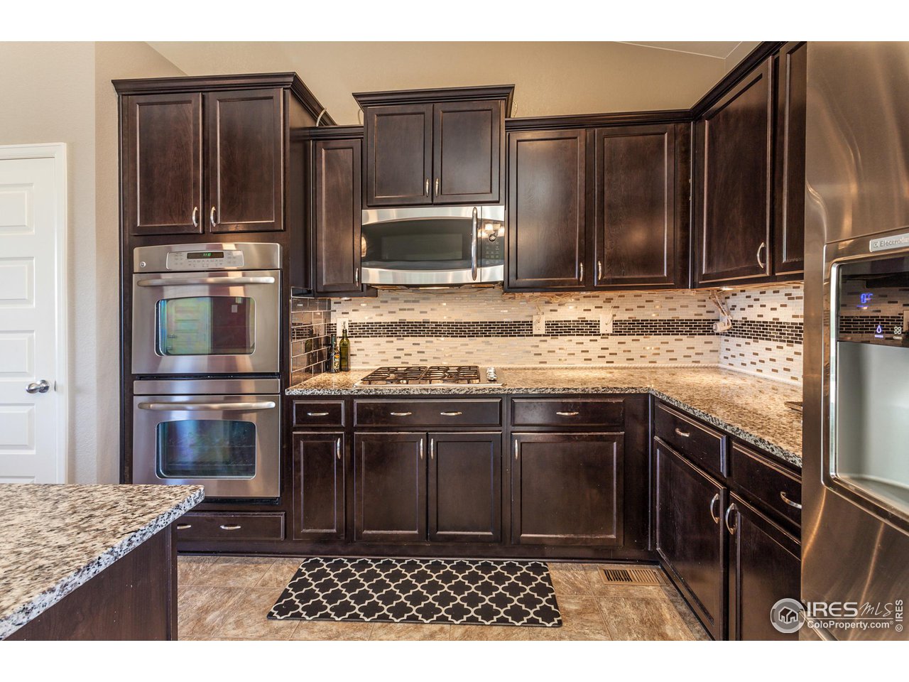 8594 Raspberry Drive Frederick, CO 80504 - Photo 9 of 40 a kitchen with kitchen island granite countertop a stove microwave and refrigerator