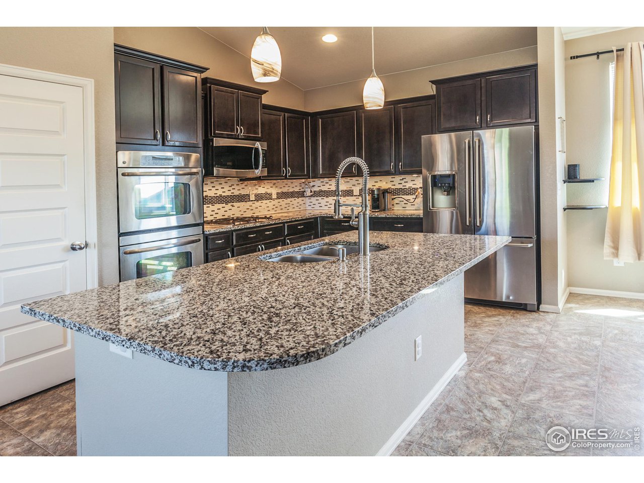 8594 Raspberry Drive Frederick, CO 80504 - Photo 10 of 40 a kitchen with stainless steel appliances granite countertop a sink refrigerator and microwave