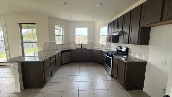a kitchen with stainless steel appliances granite countertop a stove a sink and a refrigerator