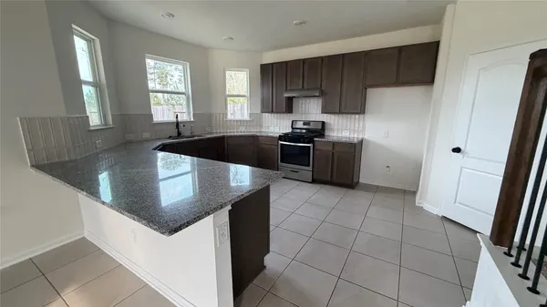 a kitchen with stainless steel appliances granite countertop a sink a stove a refrigerator and island