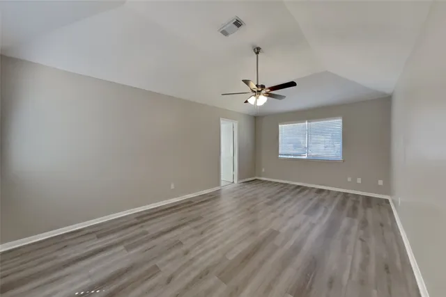 a view of an empty room and chandelier fan