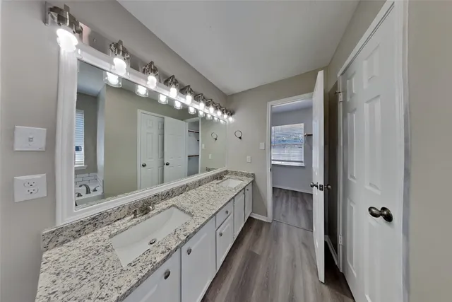 a bathroom with a granite countertop double vanity sink and mirror
