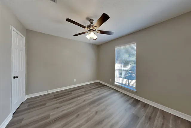 a view of an empty room with window and wooden floor