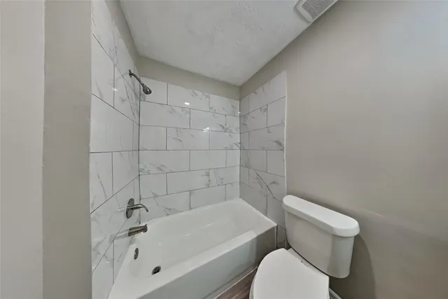 a white toilet sitting next to a bath tub
