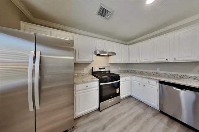 a kitchen with stainless steel appliances granite countertop a stove a refrigerator and a sink with wooden floor