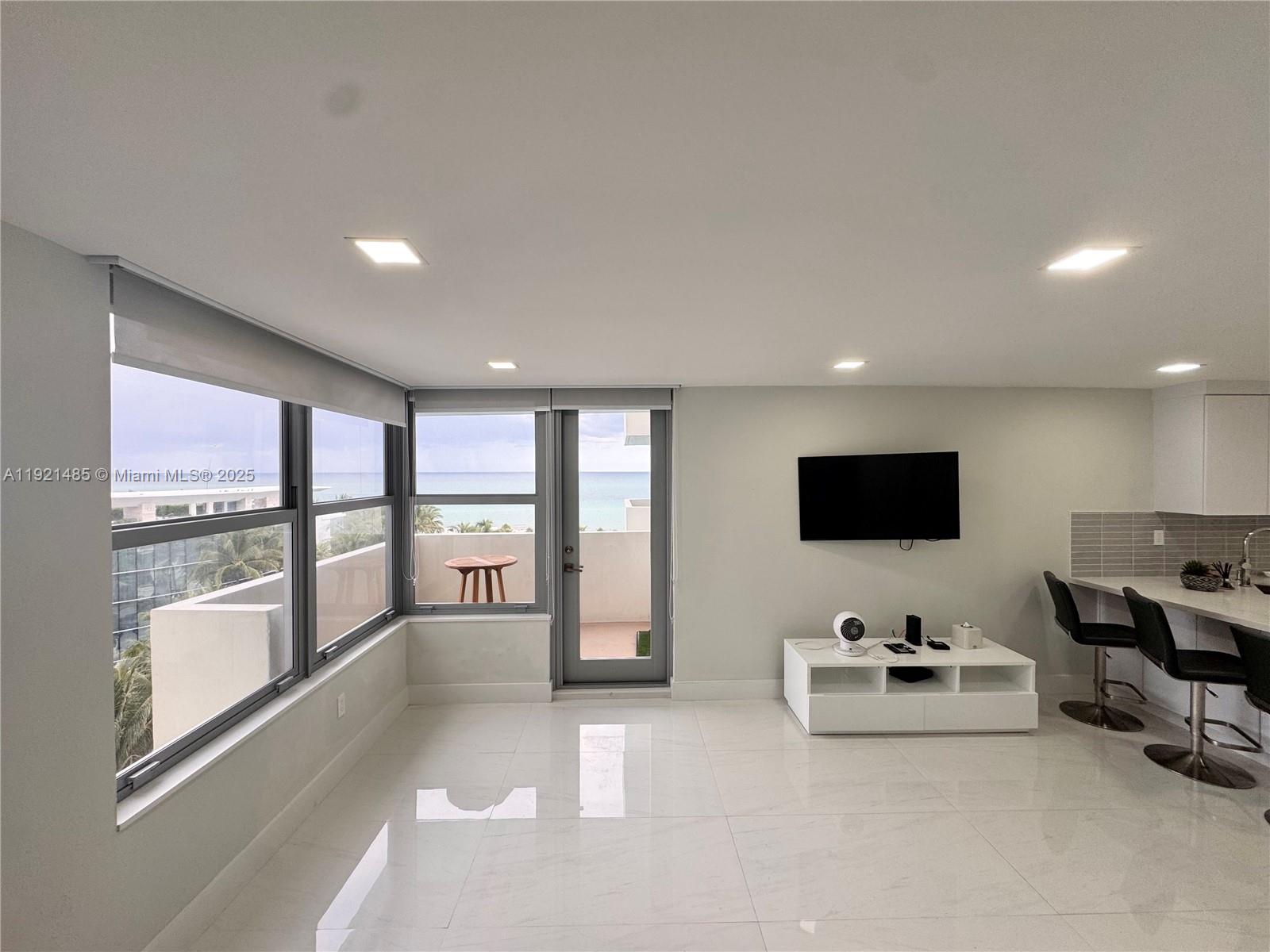 2899 Collins Avenue, Unit 915 Miami Beach, FL 33140 - Photo 2 of 31 a living room with furniture and a flat screen tv