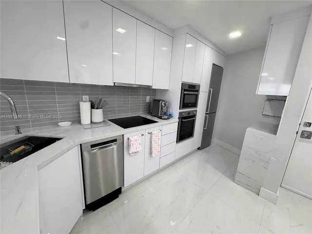 a kitchen with stainless steel appliances kitchen island granite countertop a sink and a refrigerator