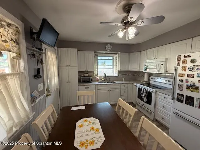 a kitchen with granite countertop a refrigerator a sink dishwasher a stove and white cabinets with wooden floor