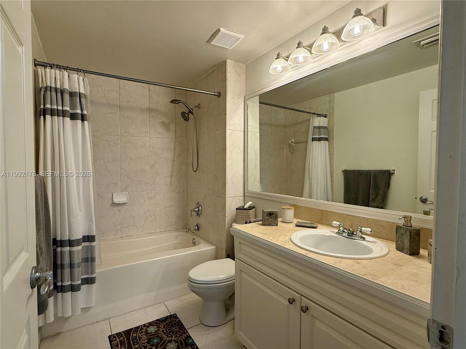 6831 Southwest 44th Street, Unit 203 Miami, FL 33155 - Photo 6 of 15 a bathroom with a granite countertop sink a toilet a mirror and shower
