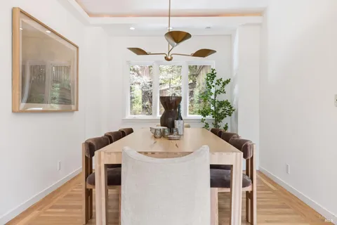 a dining room with chandelier fan and wooden floor