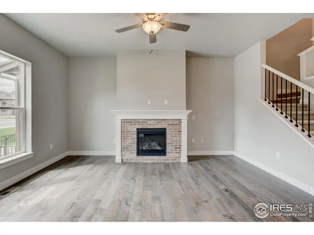 a view of an empty room with wooden floor fireplace and a window