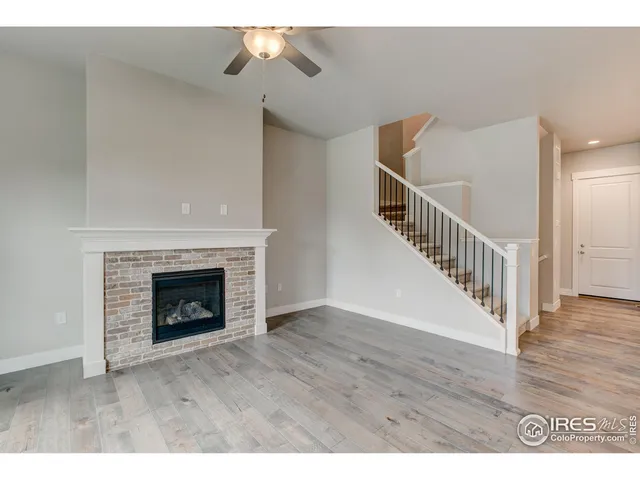 a view of an empty room with wooden floor and a fireplace