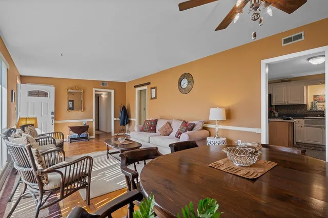 a kitchen with stainless steel appliances kitchen island granite countertop a refrigerator a stove a sink a dining table and chairs with wooden floor