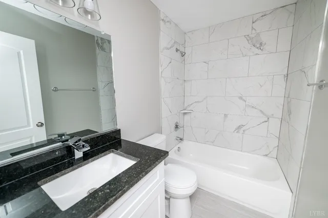a bathroom with a granite countertop sink mirror toilet and bathtub