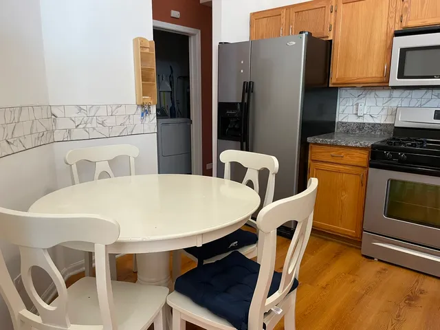 a kitchen with stainless steel appliances dining table and chairs