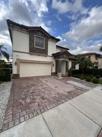 a front view of a house with a yard and potted plants