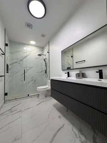 a bathroom with a double vanity sink toilet and shower