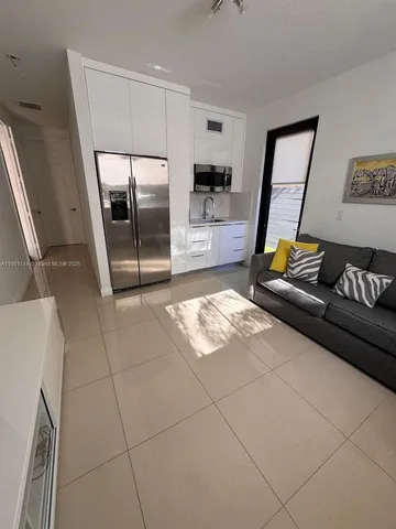 a living room with a couch and a washing machine with wooden floor