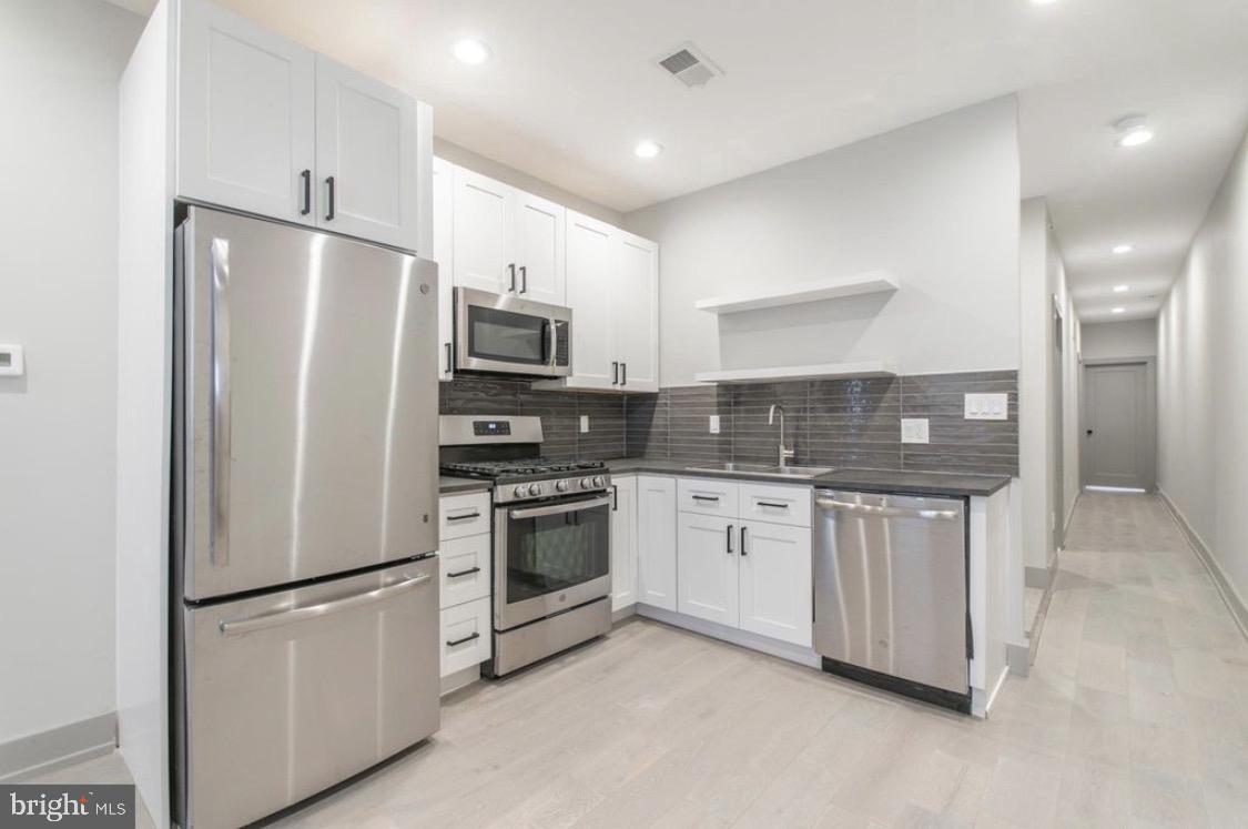 3339 Ridge Avenue Philadelphia, PA 19132 - Photo 21 of 33 a kitchen with stainless steel appliances granite countertop a refrigerator a sink a stove a microwave and island