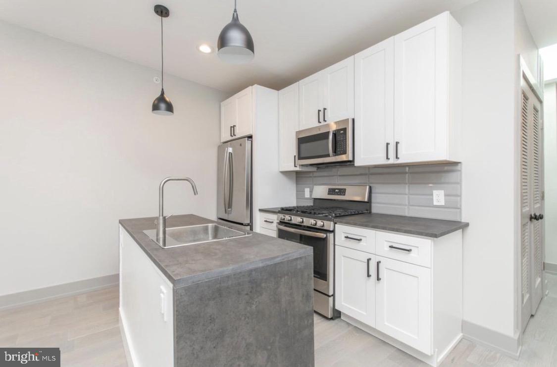 3339 Ridge Avenue Philadelphia, PA 19132 - Photo 4 of 33 a kitchen with stainless steel appliances granite countertop a sink stove microwave and refrigerator